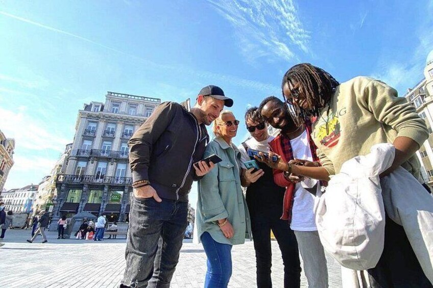 A group of people standing on a paved area with buildings in the background. 1