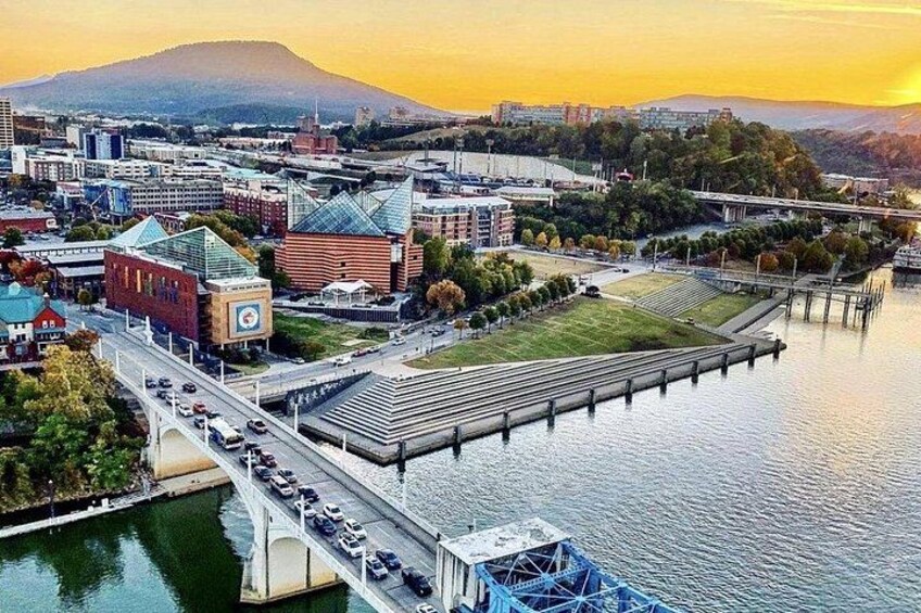 A cityscape with a bridge over water, buildings, and a mountain in the background. 4