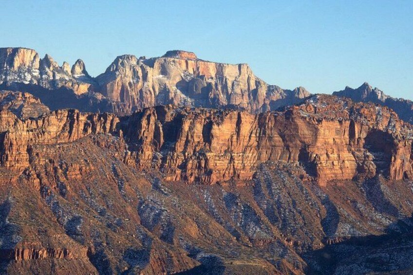Una cordillera escarpada con formaciones rocosas en capas y cielo despejado. 3