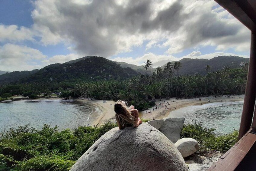 Une plage tropicale bordée de palmiers, avec un grand rocher et une chaîne de montagnes en arrière-plan. 4