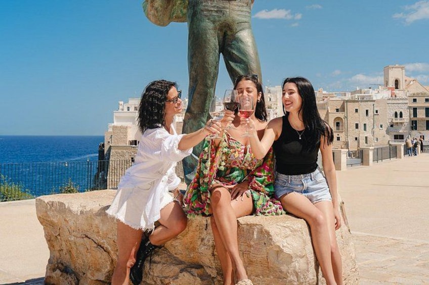 Tres personas sentadas sobre una roca, con una estatua al fondo. 5