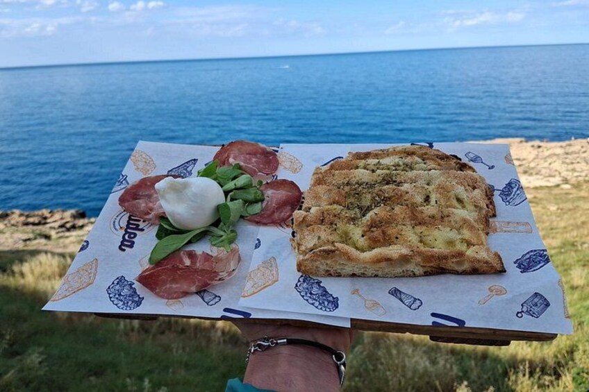 Una persona sosteniendo una bandeja con comida y vista al mar. 3