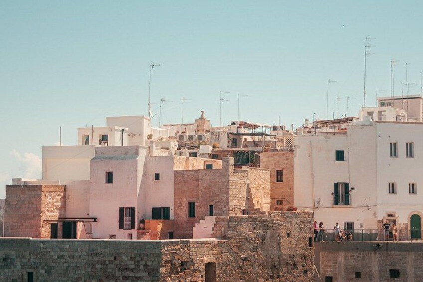 Un pueblo costero con edificios blancos, un muro de piedra y cielo despejado. 4