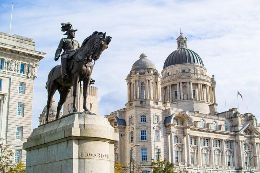 A statue of a mounted figure on a pedestal with the name 'EDWARD VII' and a large neoclassical building with domes in the background. 3