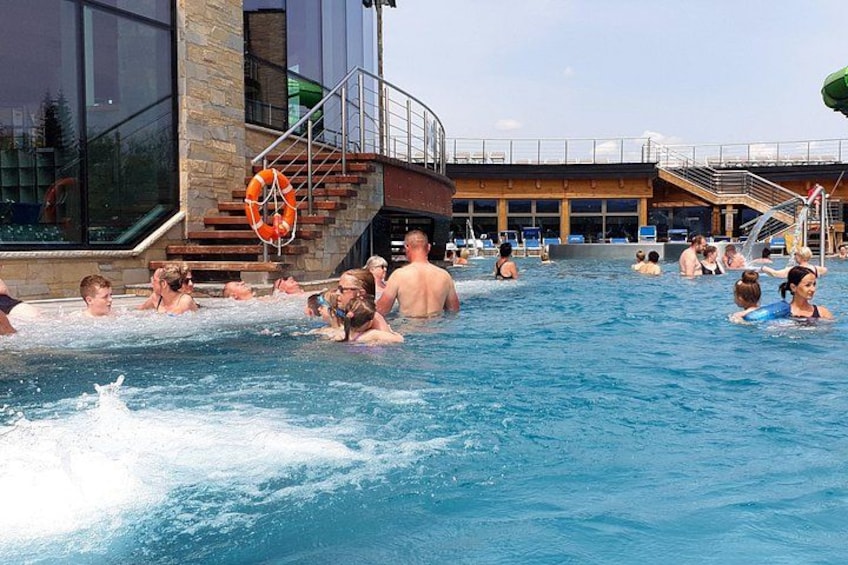A swimming pool with people in the water, a lifebuoy, and a building with stairs in the background. 2