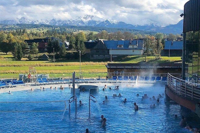 A swimming pool with people, a water fountain, and mountains in the background. 5