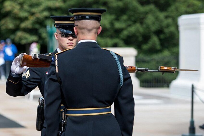 Two uniformed individuals in ceremonial attire, one holding a rifle. 2