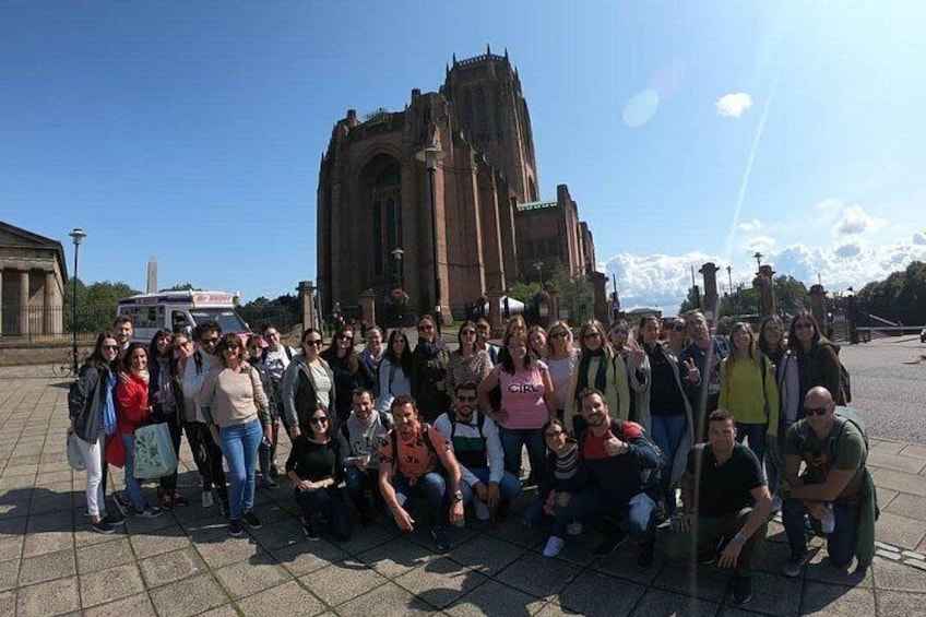 Een groep mensen die poseert voor een grote kerk met een hoge spits. 3