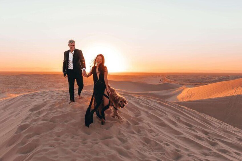 Una pareja caminando sobre una duna de arena, con el atardecer al fondo. 1
