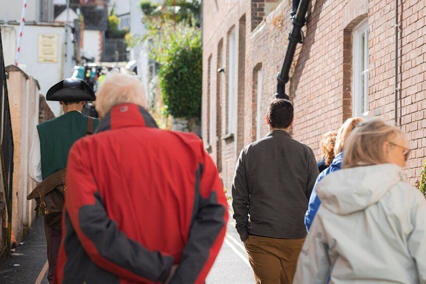 A narrow street with brick buildings, pedestrians, and a person in a red jacket. 3