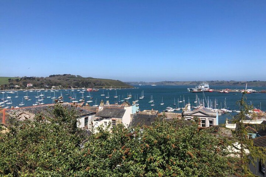 Un pueblo costero con numerosos barcos amarrados en el puerto, rodeado de vegetación y colinas al fondo. 2