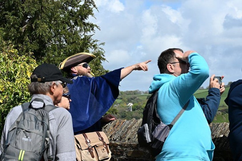 A group of people outdoors, some wearing hats and one pointing towards the horizon. 3