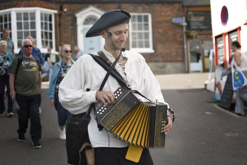 A person playing a traditional accordion outdoors. 4