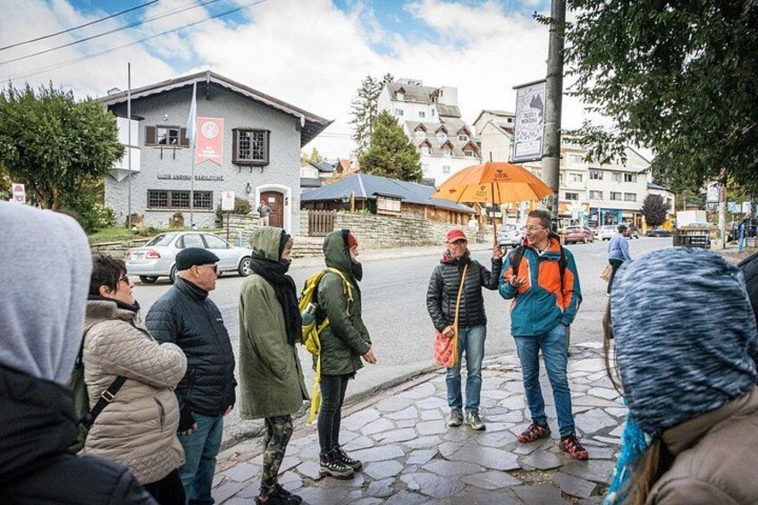 Un gruppo di persone in piedi su una strada acciottolata, un edificio con una bandiera e una persona con uno zaino. 4