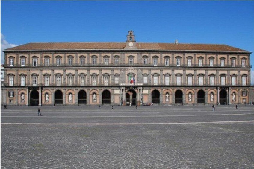 A large historic building with multiple arches and a central clock tower. 2