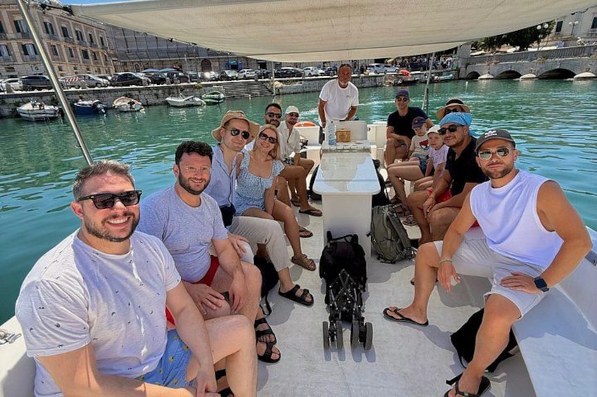 A group of people on a boat in a marina with buildings and boats in the background. 2