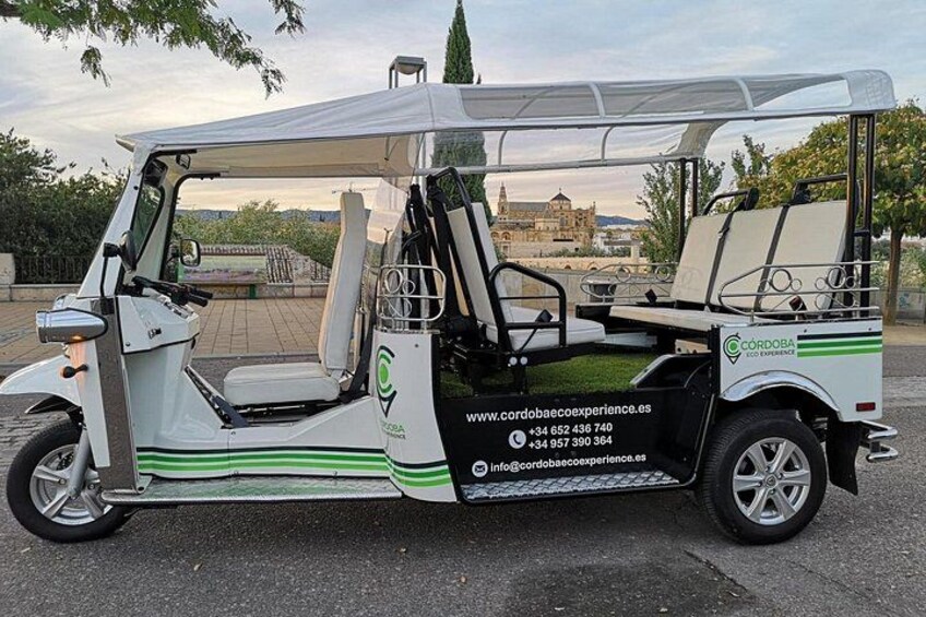 Een golfkarretje staat buiten geparkeerd, met een webadres en contactgegevens op de zijkant. 2
