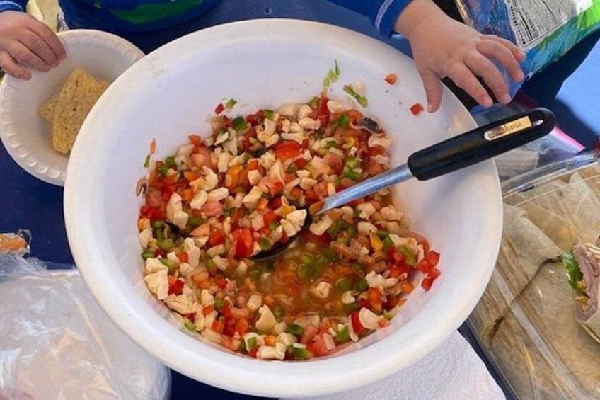 Un grand saladier blanc rempli de légumes coupés en morceaux et une cuillère à manche noir. 2