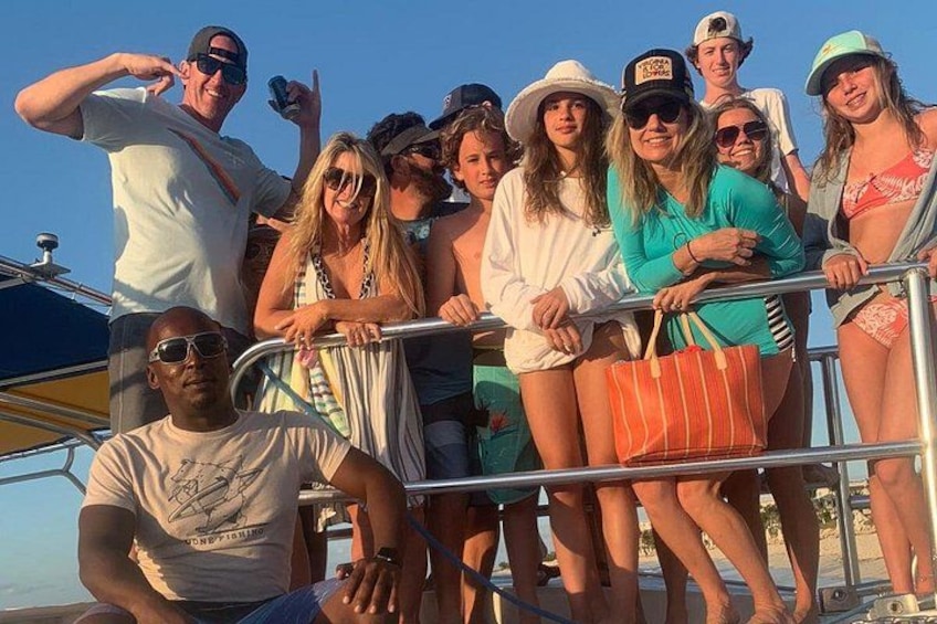 Un groupe de personnes se trouve sur un bateau, certaines portent des chapeaux et des lunettes de soleil, et un ciel dégagé se profile à l'arrière-plan. 5