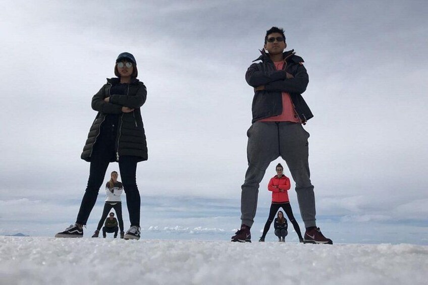 Two people standing on a snowy surface with a cloudy sky in the background. 5