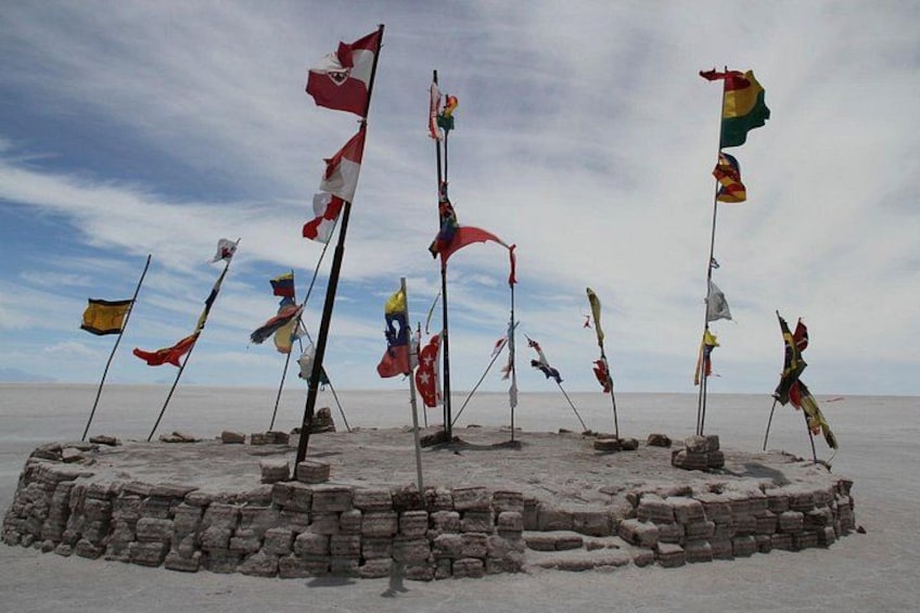 A circular stone structure with multiple flags on poles. 3