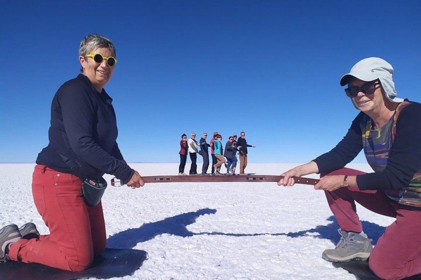 Two people pulling a sled on a snowy plain with a group of people in the background. 2