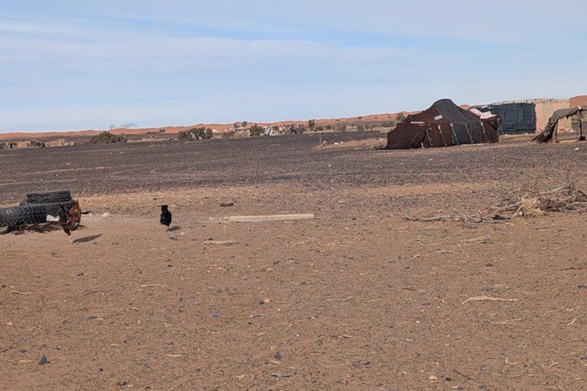 A desert landscape with tents and a small structure. 2