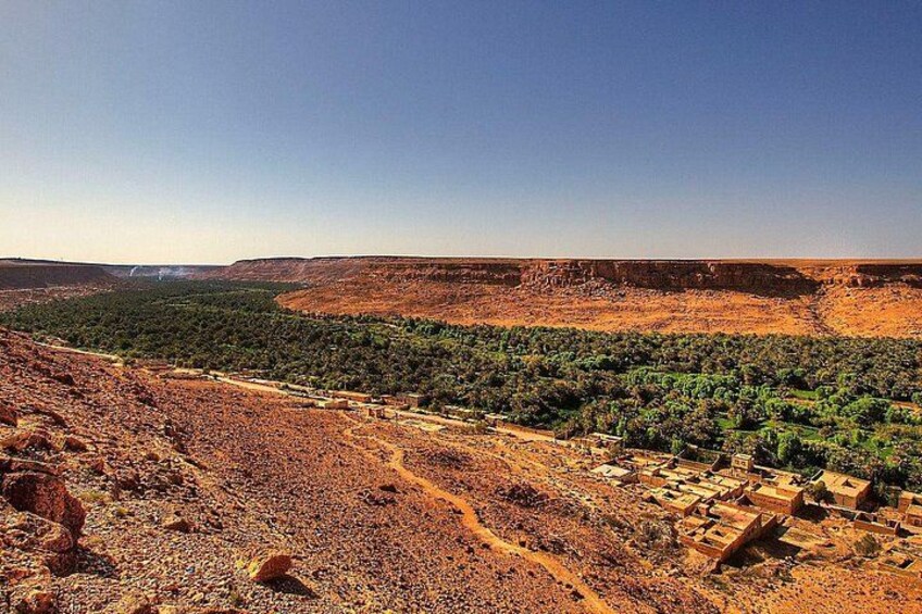 A rugged landscape with a valley, scattered buildings, and a clear sky. 5