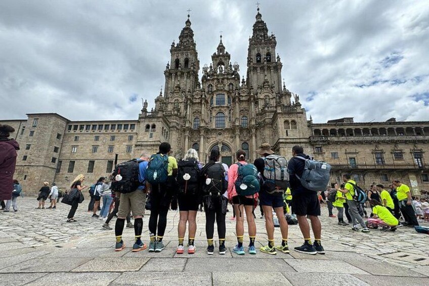 Un grupo de personas frente a una catedral grande y ornamentada con dos torres. 1