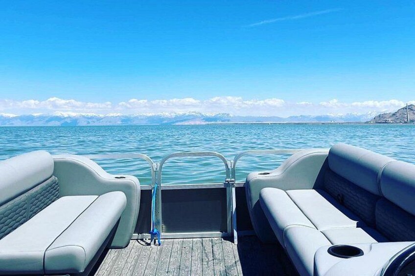 A boat deck with two white cushioned seats and a metal railing. 1