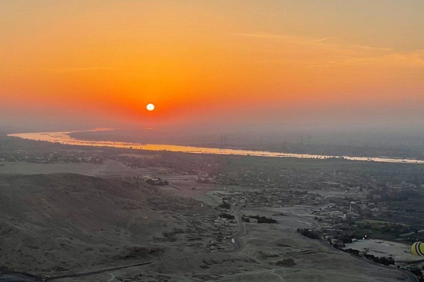 Un coucher de soleil sur une rivière, avec une vue sur la ville en arrière-plan. 5
