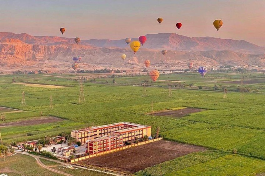 Un festival de montgolfières avec de nombreuses montgolfières dans le ciel, un grand bâtiment avec un toit rouge et un paysage montagneux en arrière-plan. 3
