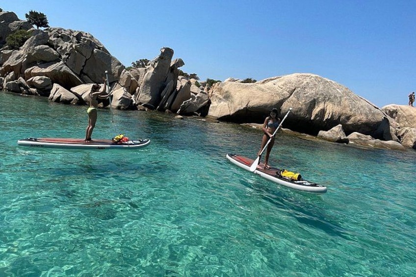 Dos tablas de remo en agua turquesa cristalina con grandes rocas al fondo. 5