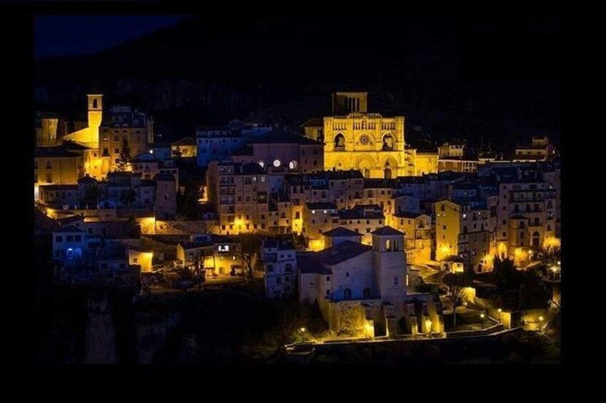 A town at night with illuminated buildings and a prominent church. 1