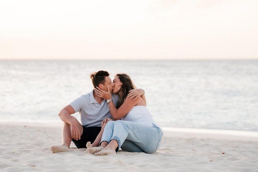 A couple sitting on a beach with the ocean in the background. 4