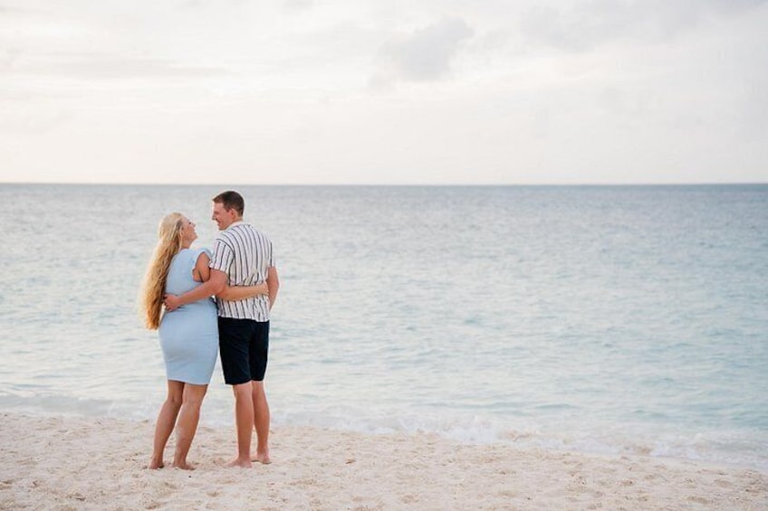 A couple embracing on a beach with the ocean in the background. 2