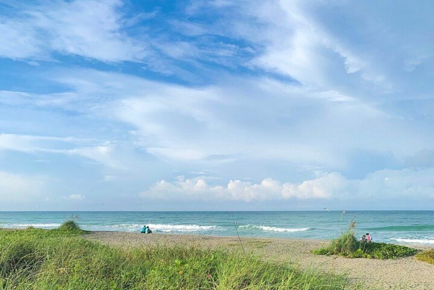 A beach with waves, a person sitting, and another person walking. 3
