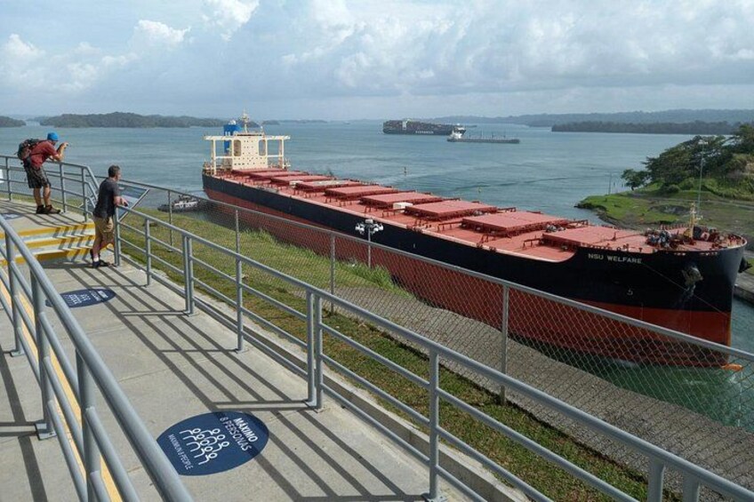 A large cargo ship named NSU Welfare docked at a port with a person taking a photo. 2
