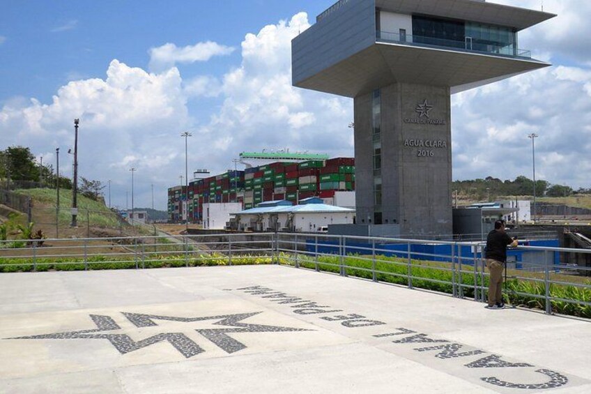 A modern building with a sign reading 'AGUA CLARA 2016' and a large star symbol on the ground. 4
