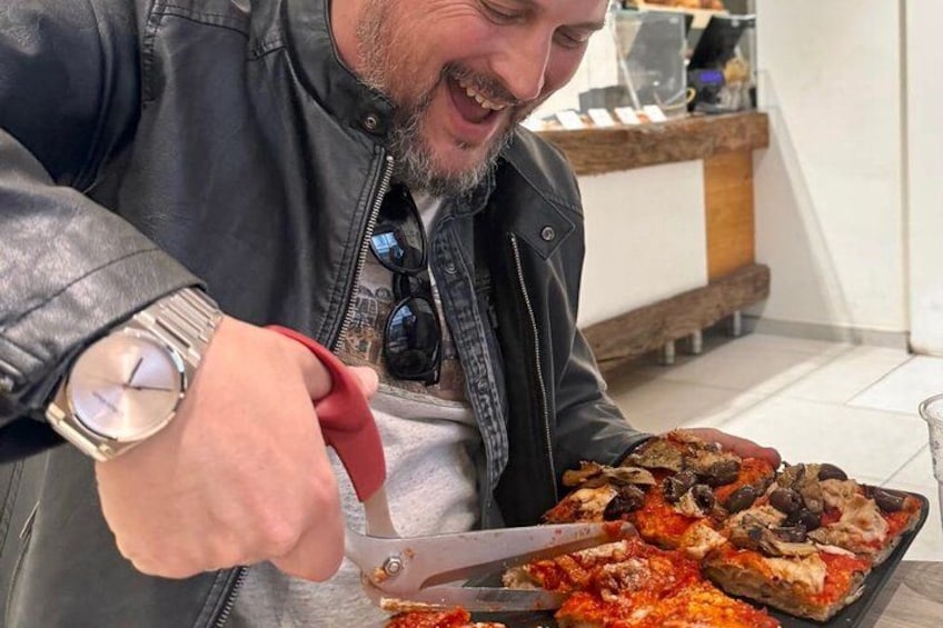 A person cutting a pizza with a pizza cutter. 2