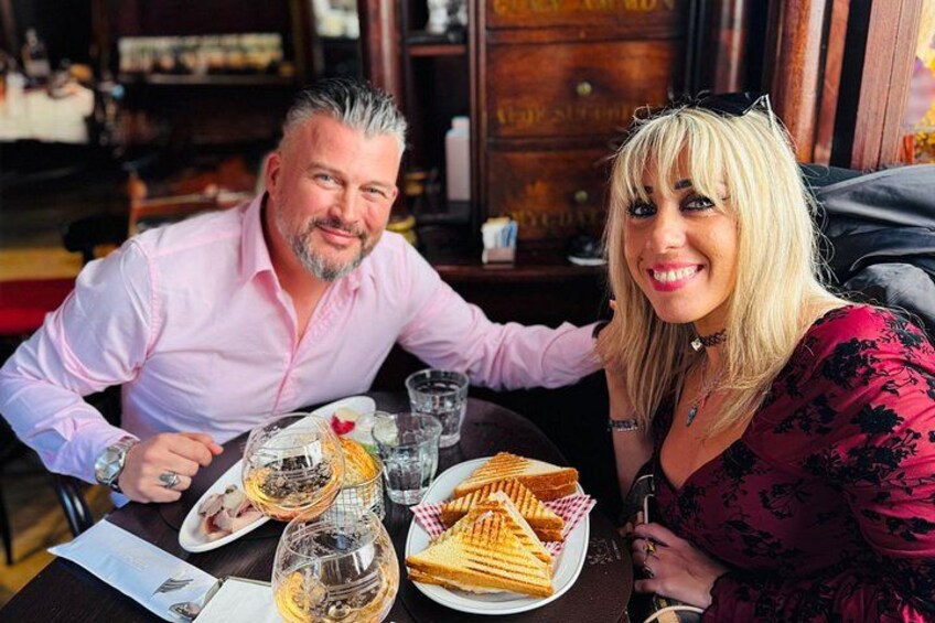 Two people sitting at a table with food and drinks. 2