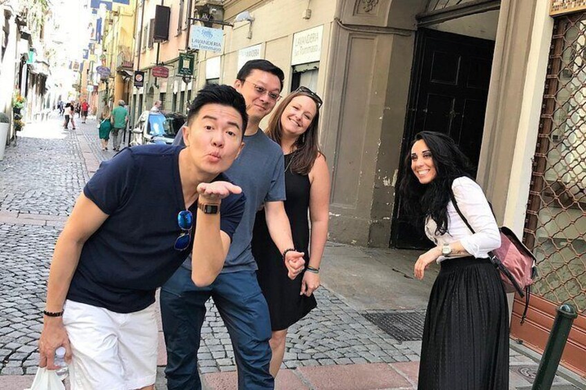 A cobblestone street with buildings, a person blowing a kiss, and another person holding a drink. 3
