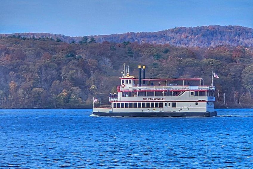 A riverboat named 'Rip Van Winkle' on a body of water with a forested hill in the background. 2