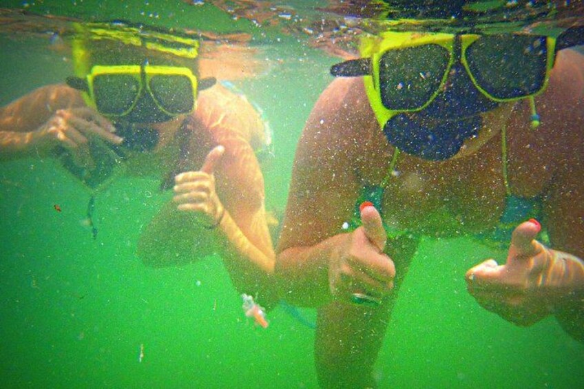 Två personer under vattnet, de har snorkelmasker på sig och visar tecknet ”tummen upp”. 3