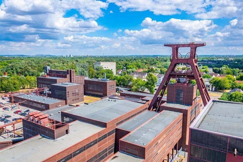 A large industrial complex with multiple buildings and a prominent red metal structure. 1