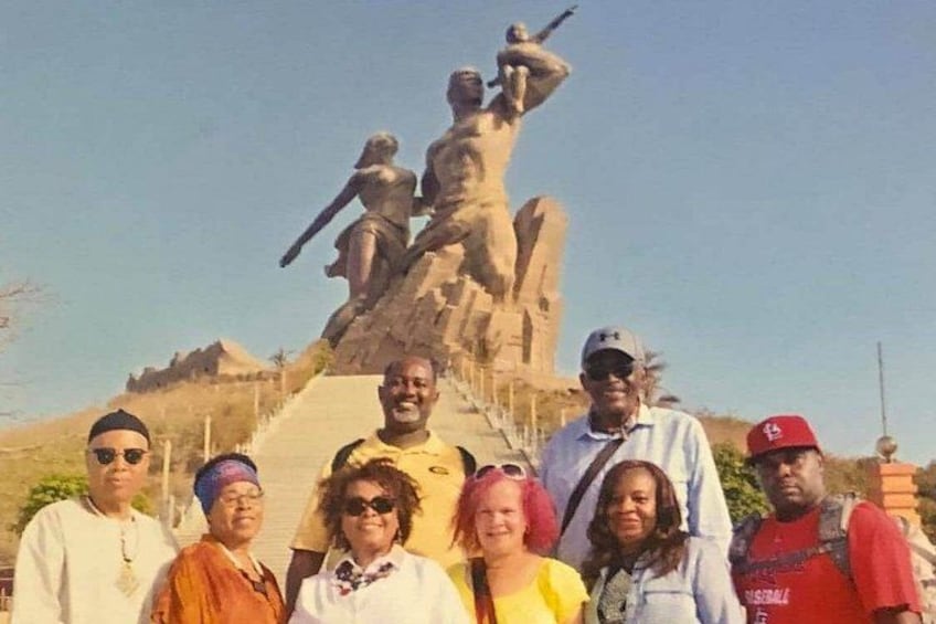 A group of people standing in front of a large statue. 1