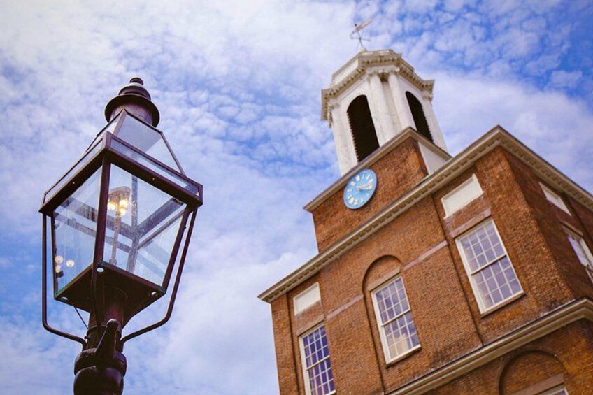 A brick building with a clock tower and a street lamp. 2