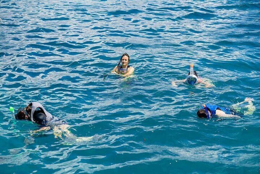 Drei Personen beim Schnorcheln in klarem, blauem Wasser. 3