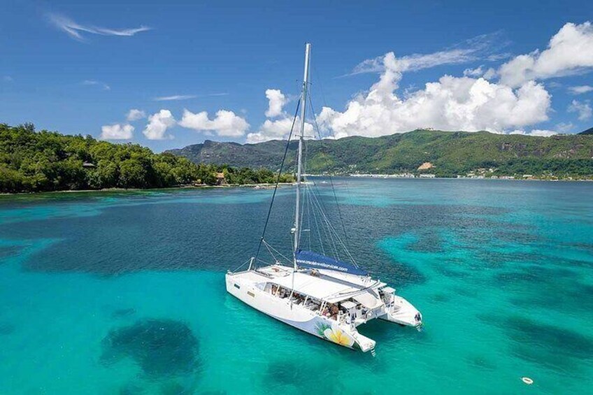 A white catamaran sailing in turquoise waters with a mountainous backdrop. 3