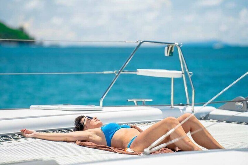 A person lying on a sun lounger on a boat with a view of the ocean. 4